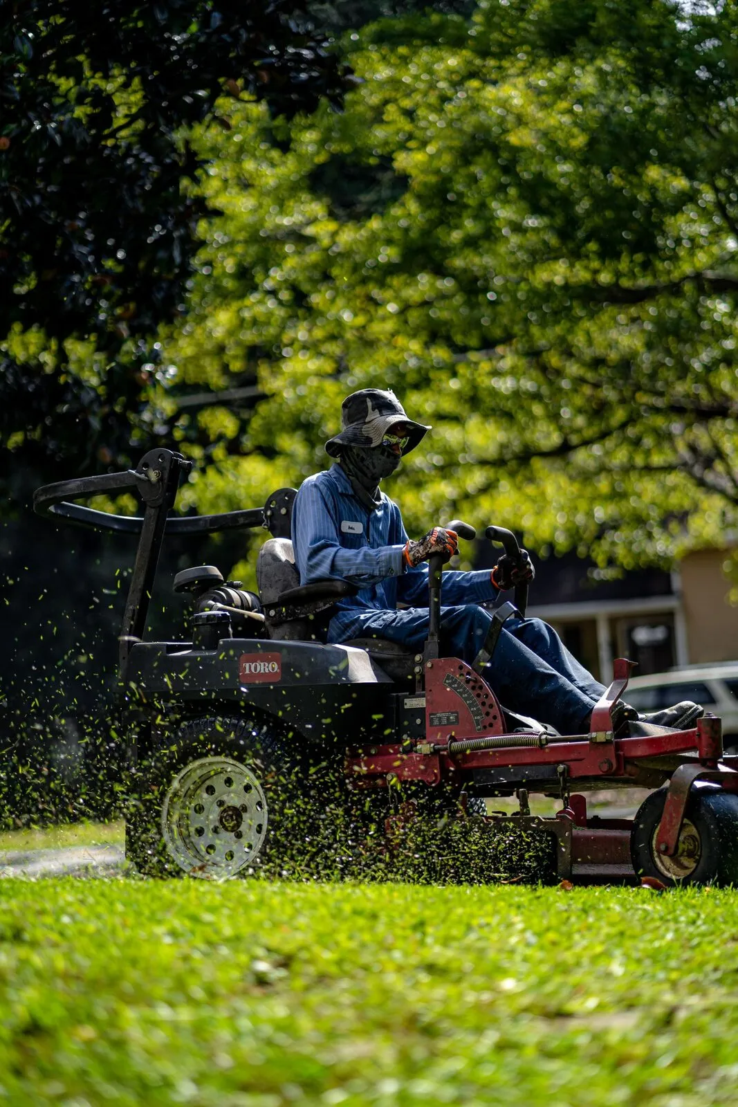 A crew member mowing a commercial lawn on a ride-on mower